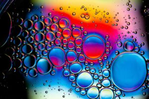 Large and small colored bubbles in fluid, some blue, some red, some mixed.